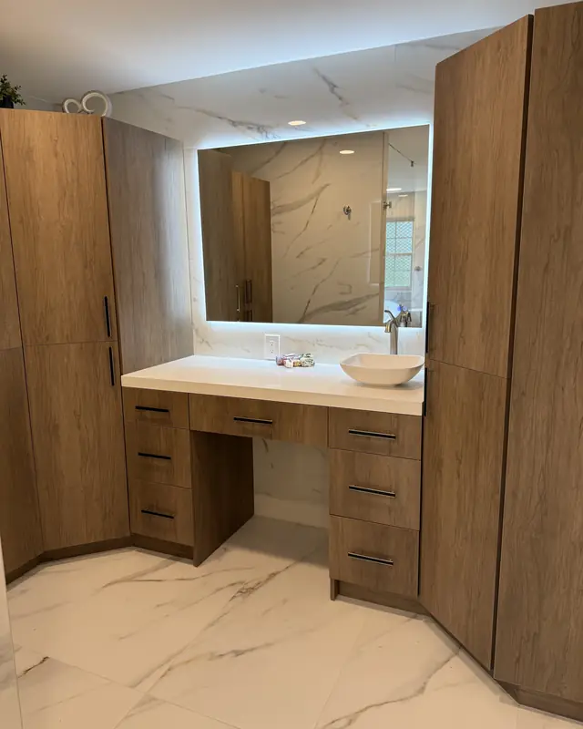 Finished primary bathroom with a walnut-look tall cabinet, makeup vanity and backlit mirror