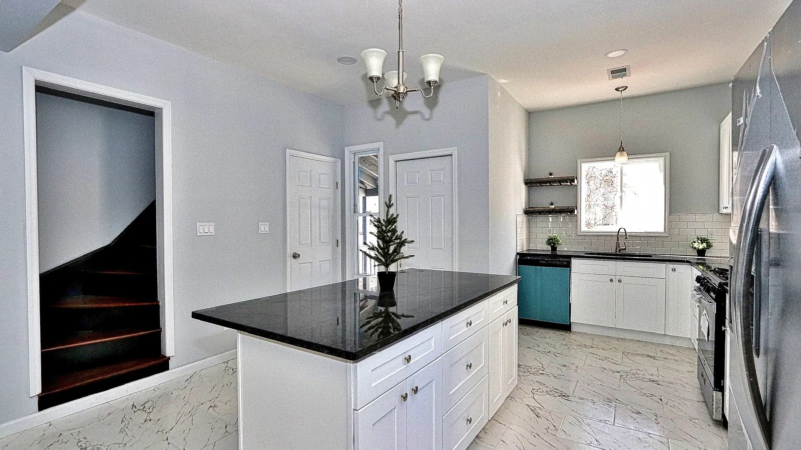 White shaker kitchen with a large quartz island, pendant lights and stainless appliances