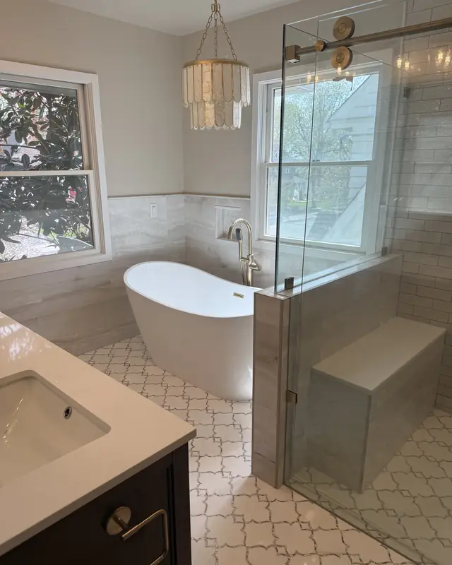Freestanding tub by the window under a shell chandelier, next to the glass shower